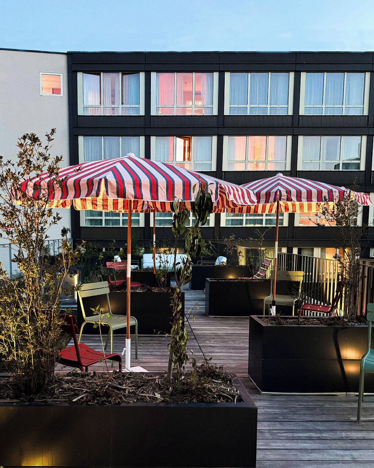 An outdoor seating area with striped umbrellas, chairs, and planters.