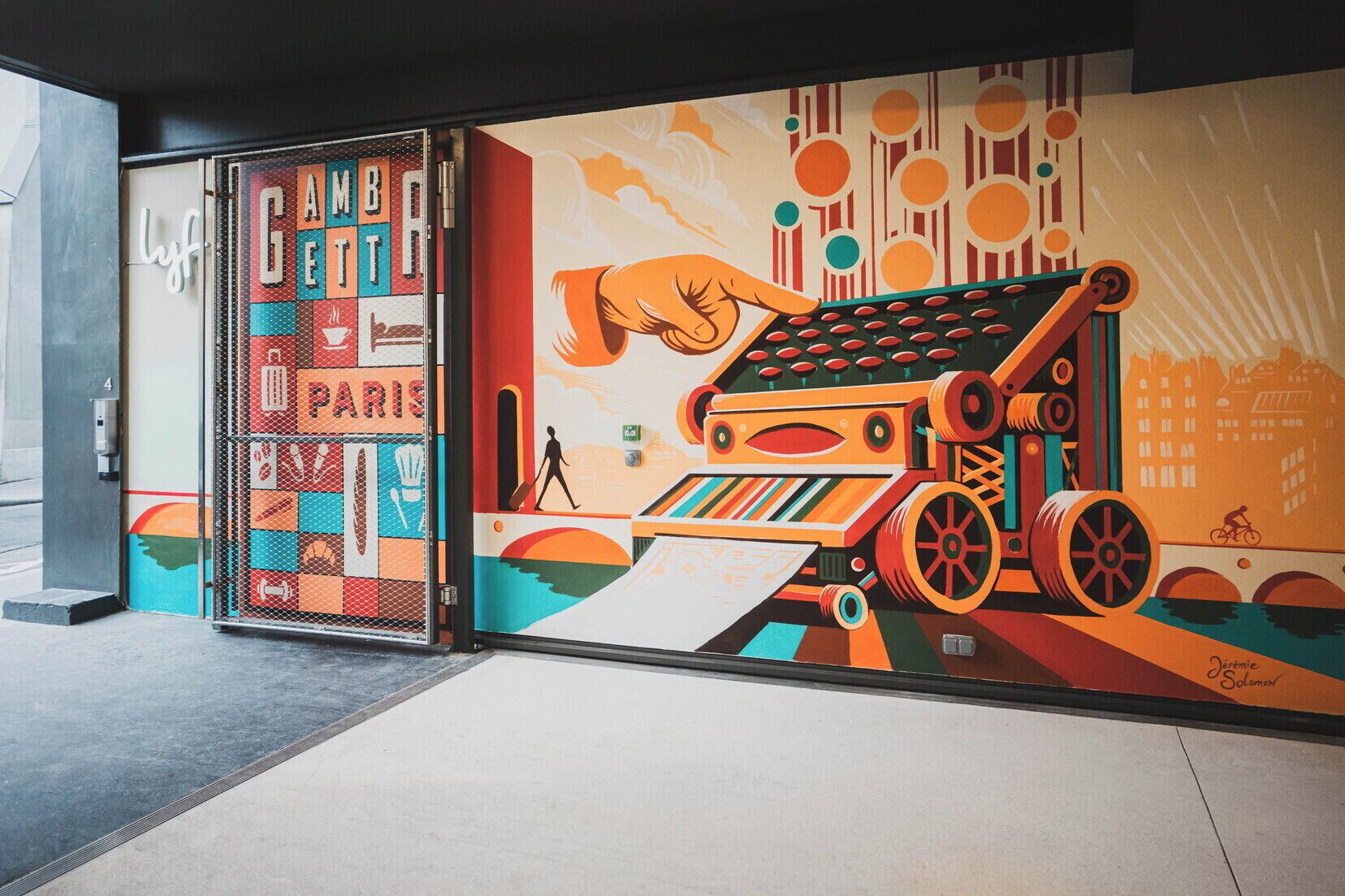 Un mural con una máquina de escribir antigua, formas abstractas y un paisaje urbano.