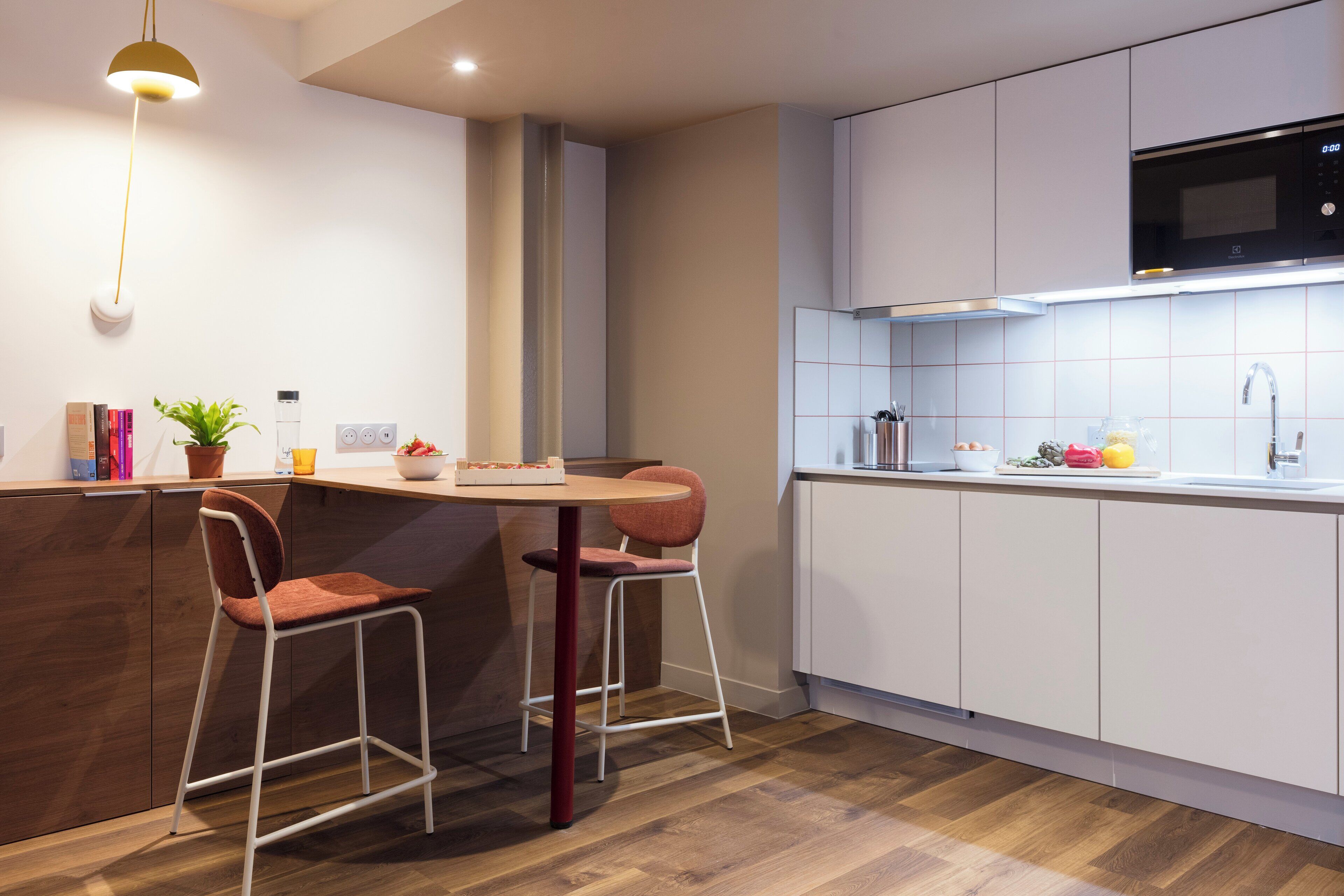 A modern kitchen with white cabinets, a wooden countertop, and two red bar stools.