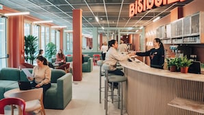 Un café moderne doté d’un bar, de différents espaces pour s’asseoir et d’un tableau des menus bien visible.