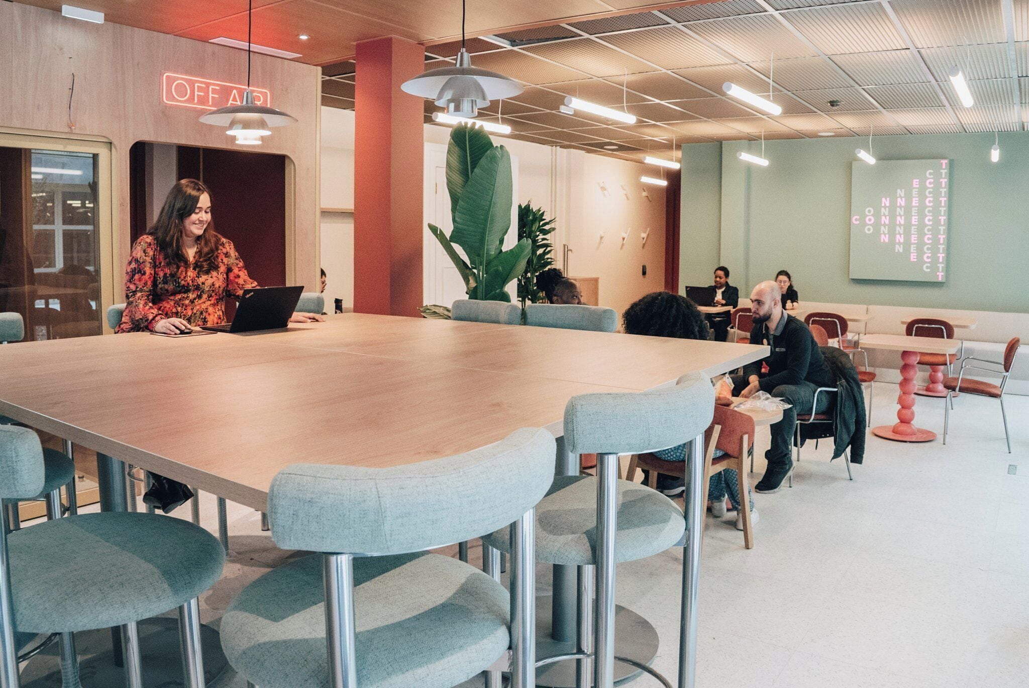 Uma sala de reunião moderna com uma mesa grande, assentos confortáveis e uma placa visível com a inscrição 'OFF AIR'.