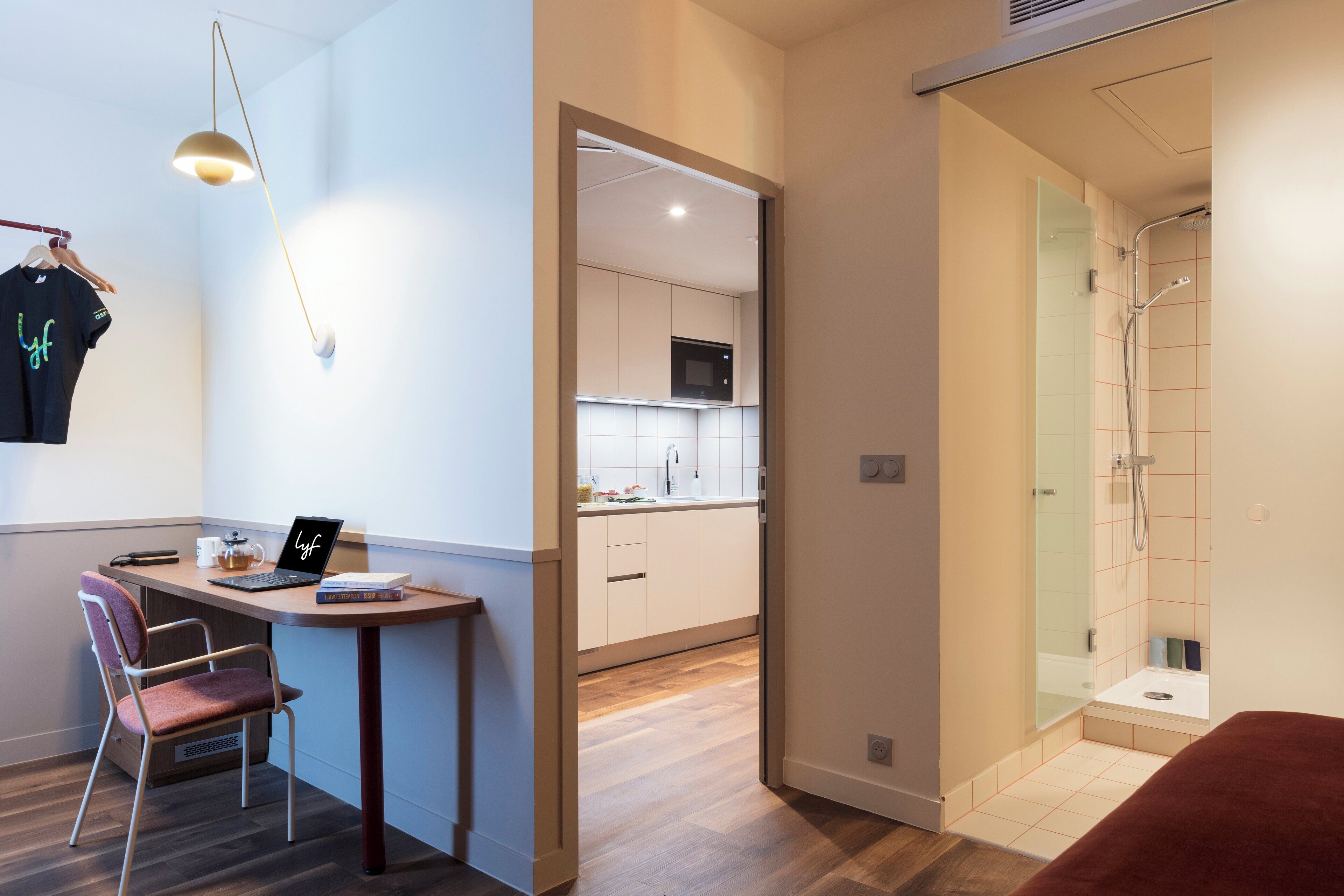 A modern hotel room with a desk, chair, and a shower area.