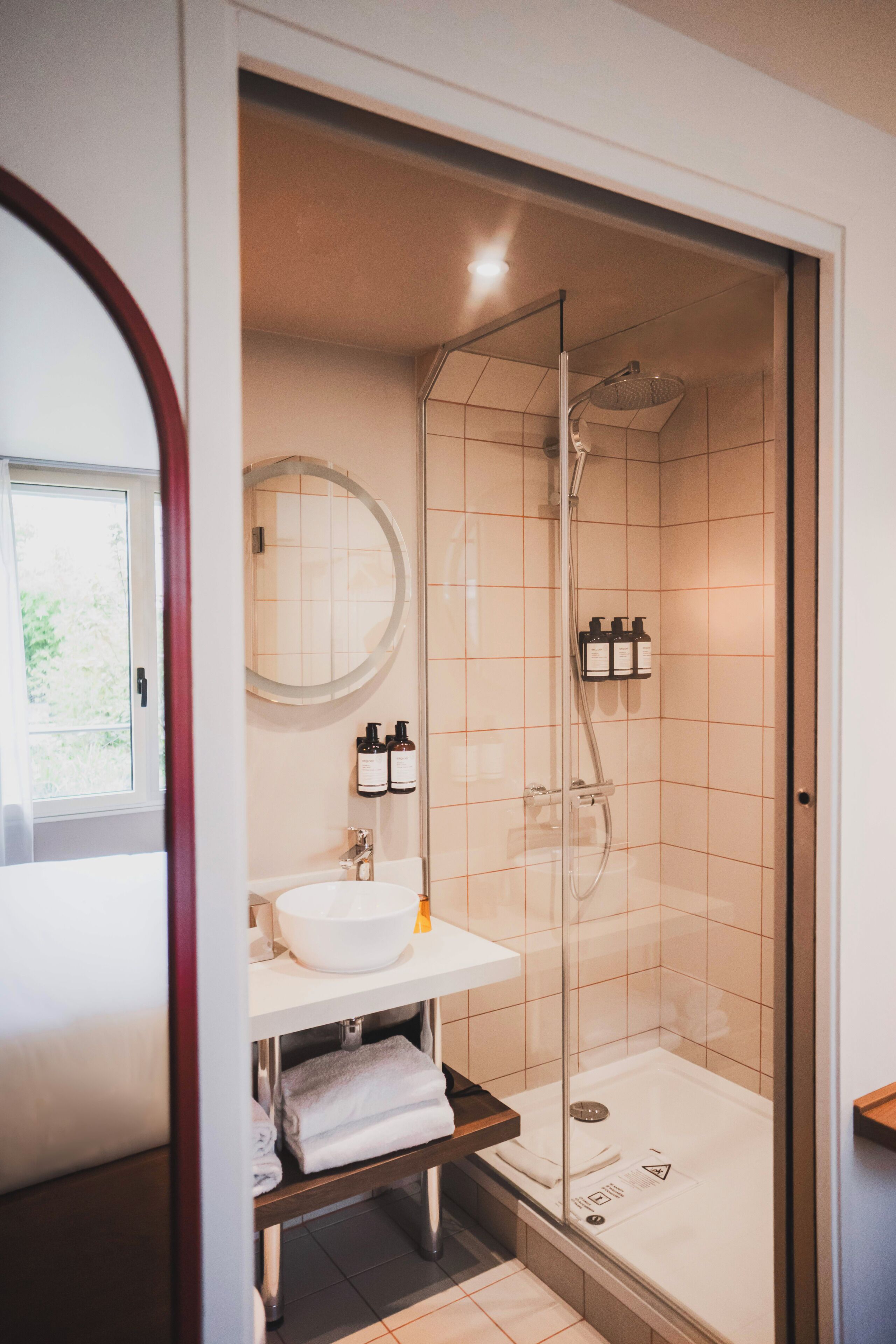 A modern bathroom with a glass-enclosed shower, a white sink, and a mirror.