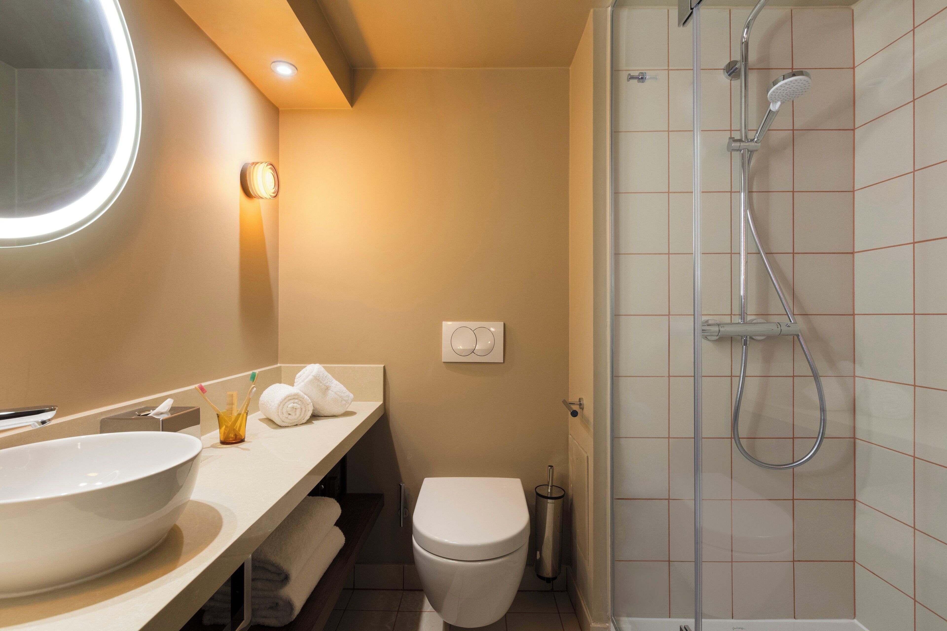 A modern bathroom with a large sink, toilet, and shower.