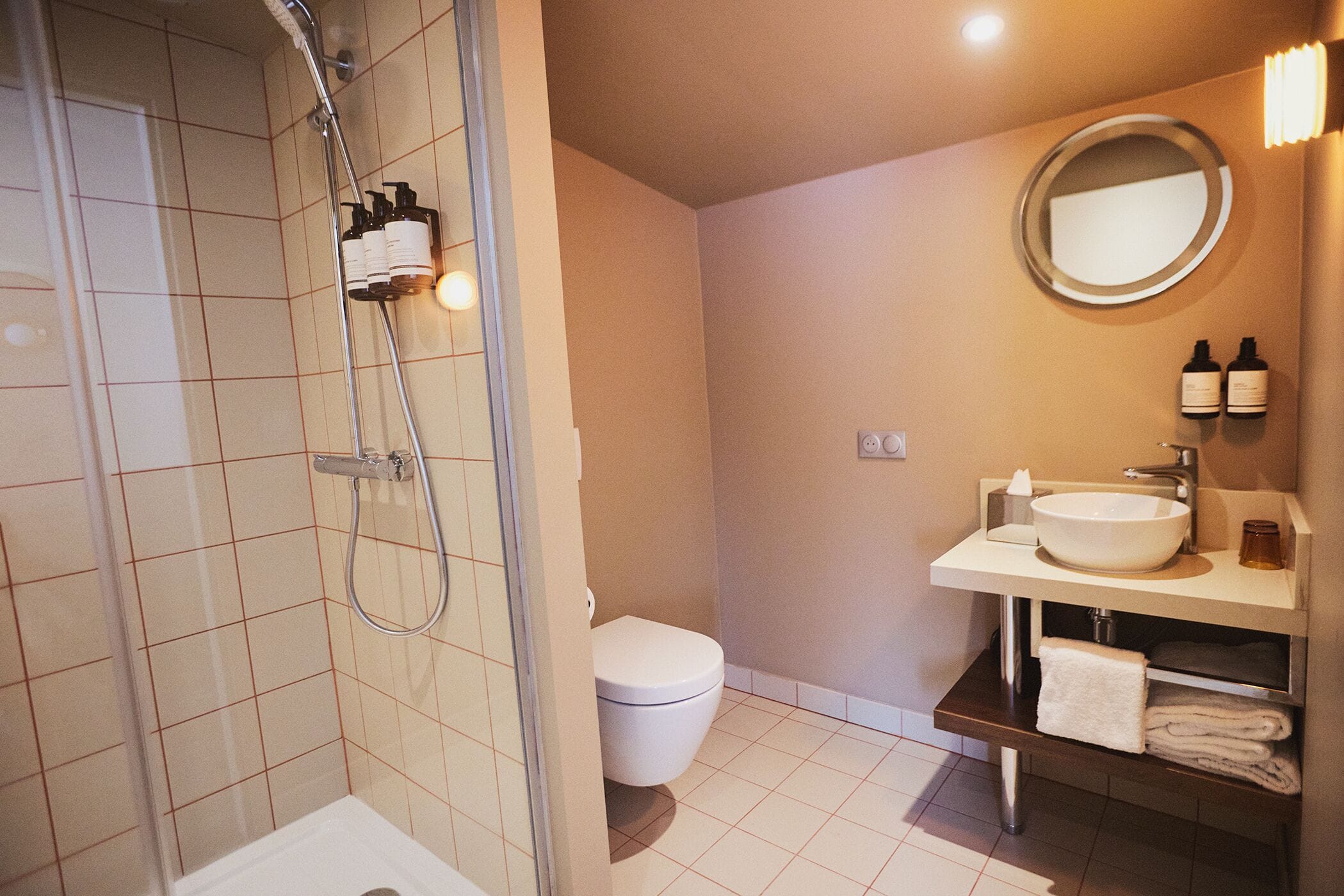 Une salle de bain équipée d’une douche, de toilettes, d’un lavabo et d’un miroir.
