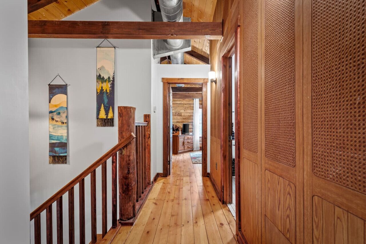 A wooden staircase leading to a loft area with a high ceiling and exposed ductwork.