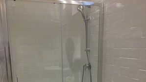 Et moderne badeværelse med et glasbadeværelse, en hvid vask på fod og et toilet.