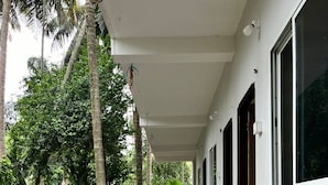 A covered walkway with a tiled floor, surrounded by lush greenery and palm trees.