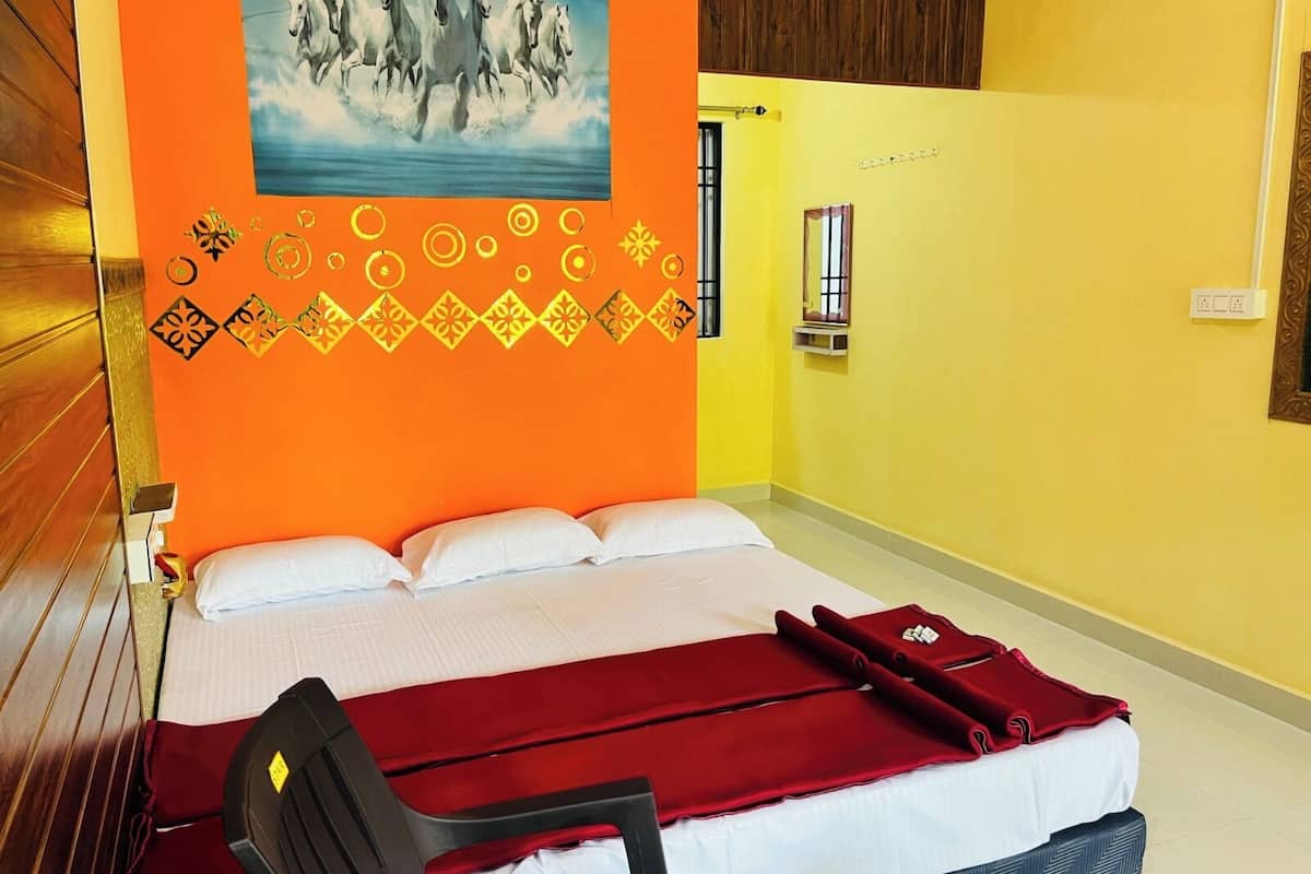 A hotel room with a bed, a chair, a red blanket, and a painting of horses on the wall.