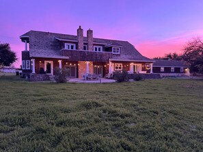 A two-story house with a large front porch, stone chimneys, and a well-maintained lawn.