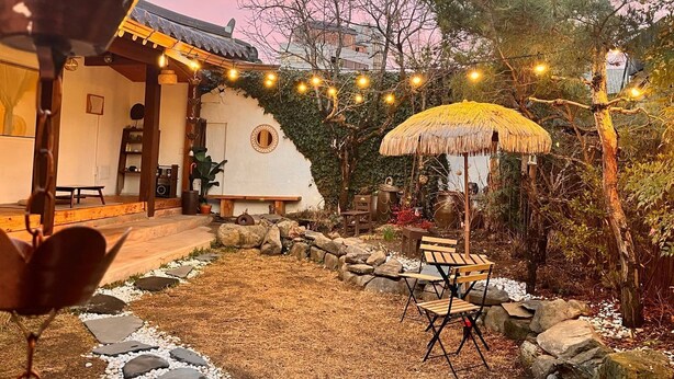 A traditional Japanese-style building with a thatched umbrella, stone pathway, and outdoor seating area.