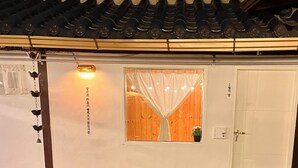 A traditional Japanese-style building with a tiled roof, a wooden door, and a window with a curtain.