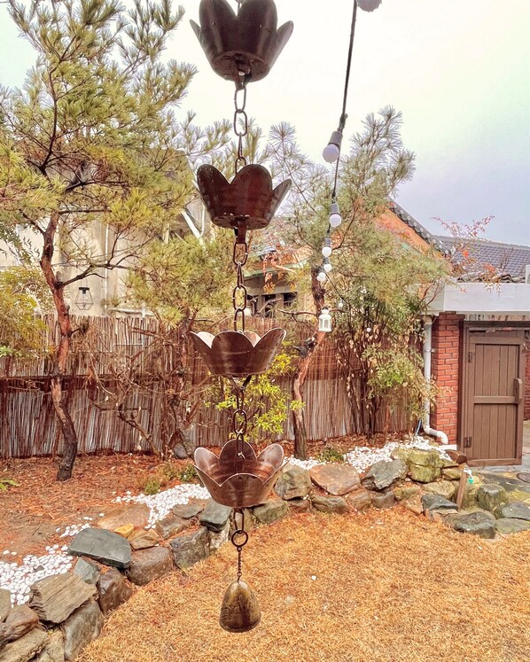 A garden with a decorative metal wind chime hanging from a tree.