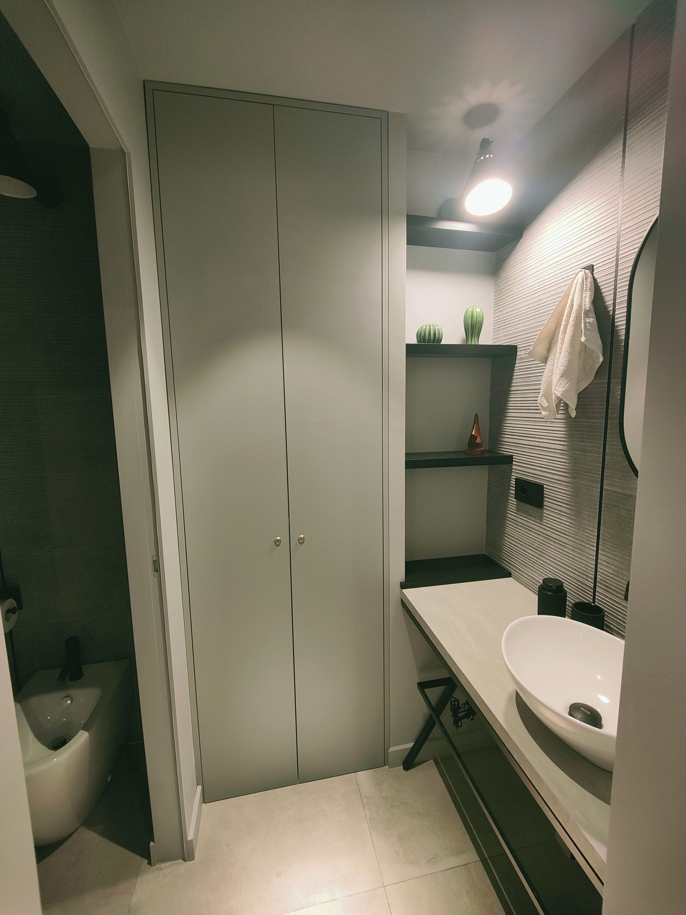 A modern bathroom with a white sink, a towel rack, and a toilet.