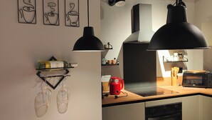 Una cocina moderna con lámparas colgantes, una mesa de madera y un hervidor rojo.