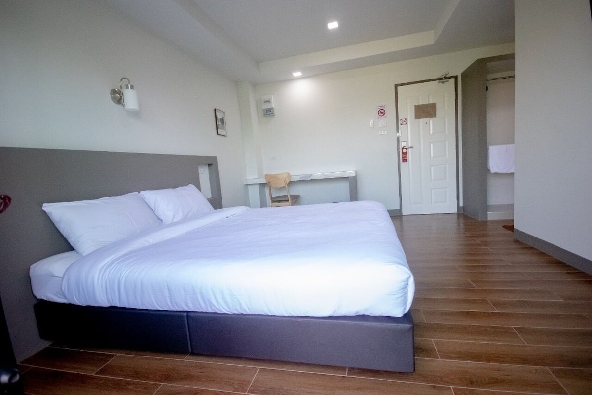 A bedroom with a bed, a desk, and a chair.