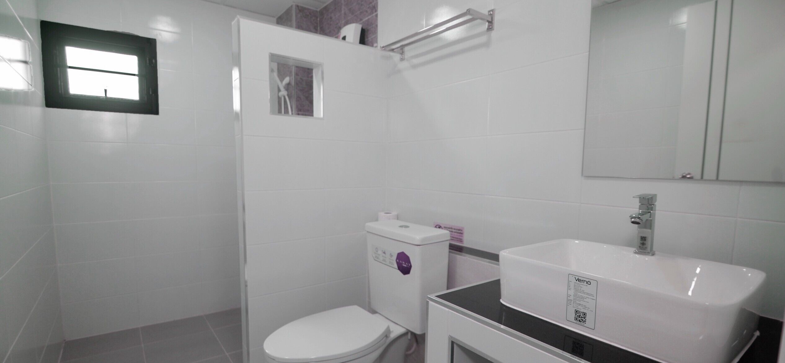 Un baño con inodoro, lavamanos, espejo y ventana.