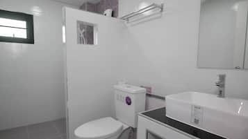 A bathroom with a toilet, sink, mirror, and a window.