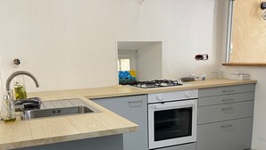 A modern kitchen with a stainless steel sink, a gas stove, and a built-in oven. - MAISON RURAL A ST CLEMENT DE VALORGUE  (Saint-Clément-de-Valorgue)