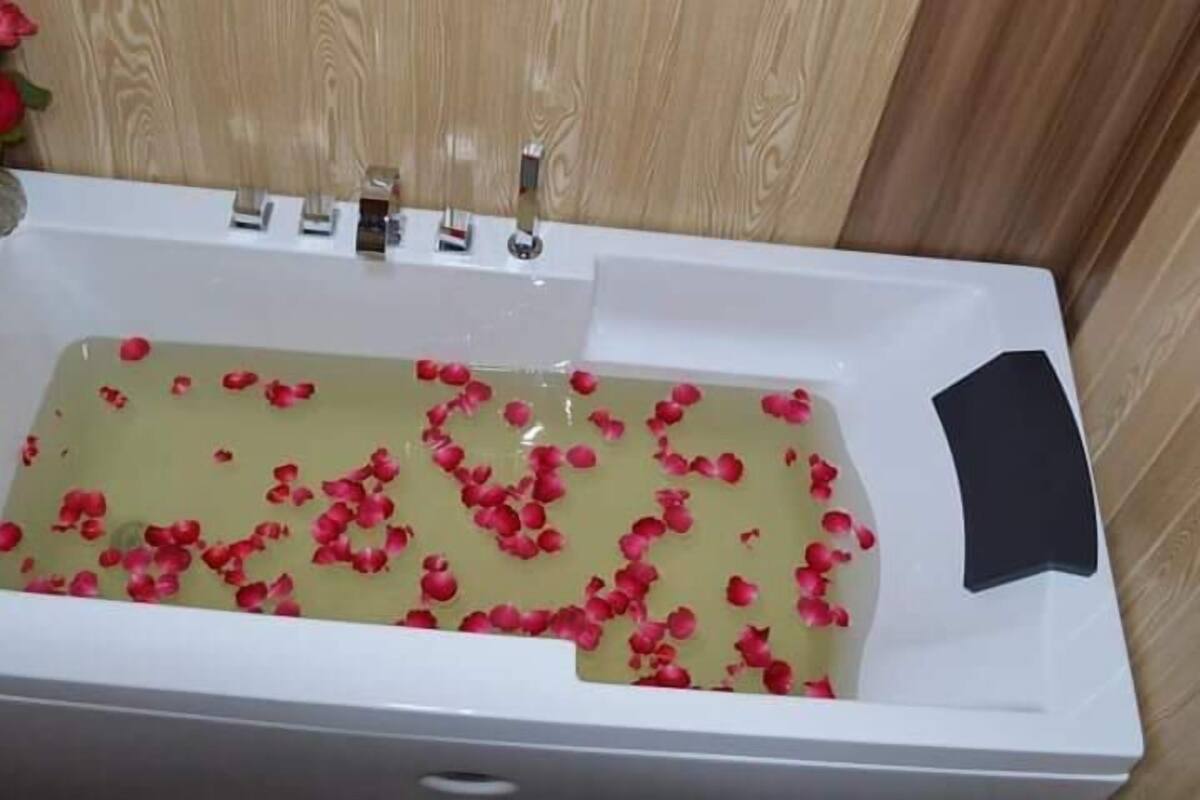 A bathtub filled with water and rose petals.