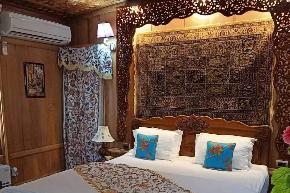 A wooden-paneled room with a large bed, patterned curtains, and a decorative headboard.