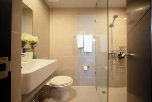 Ein modernes Badezimmer mit einer Duschkabine aus Glas, einem weißen Waschbecken und einer Toilette.