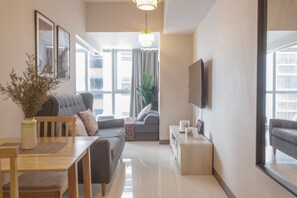 Un salon moderne avec un canapé, une table à manger et un téléviseur fixé au mur.