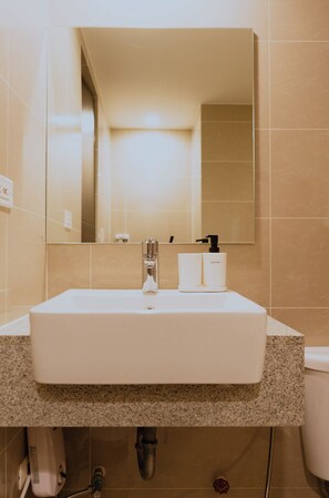 Une salle de bain avec un lavabo blanc, un miroir et un distributeur de savon liquide.
