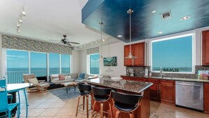 Una cocina moderna con una isla grande, taburetes de bar y vista al océano.