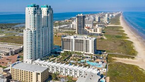 Un hotel moderno de gran altura con varias plantas, un área de piscina y vistas a la playa.