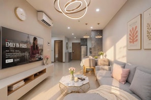 A modern living room with a flat-screen TV, a sofa, a coffee table, and a dining area with a table and chairs.