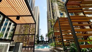 Un entorno urbano moderno con rascacielos, una pérgola de madera y una piscina.