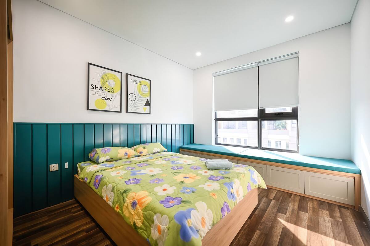 Un dormitorio con una cama, una ventana y dos cuadros en la pared.