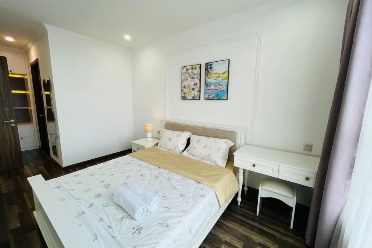Ein Schlafzimmer mit Bett, Nachttischen, einem Schreibtisch und Bildern an der Wand.