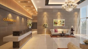 A modern reception area with a marble reception desk, a white sofa, and a chandelier. - Charmington La Pointe - Central Suites D (Ho Chi Minh City)