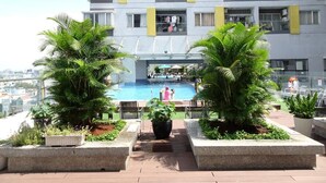 A modern hotel with a rooftop pool, surrounded by potted plants and a clear view of the cityscape. - Charmington La Pointe - Central Suites D (Ho Chi Minh City)