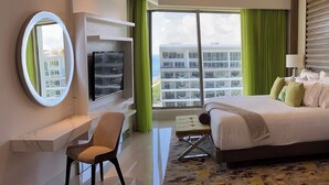 Een moderne hotelkamer met een bed, een bureau, een stoel, een televisie en een groot raam met uitzicht op de stad.