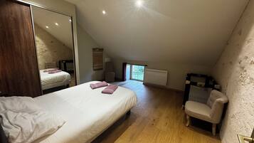 A bedroom with a large bed, a chair, a radiator, and a window.