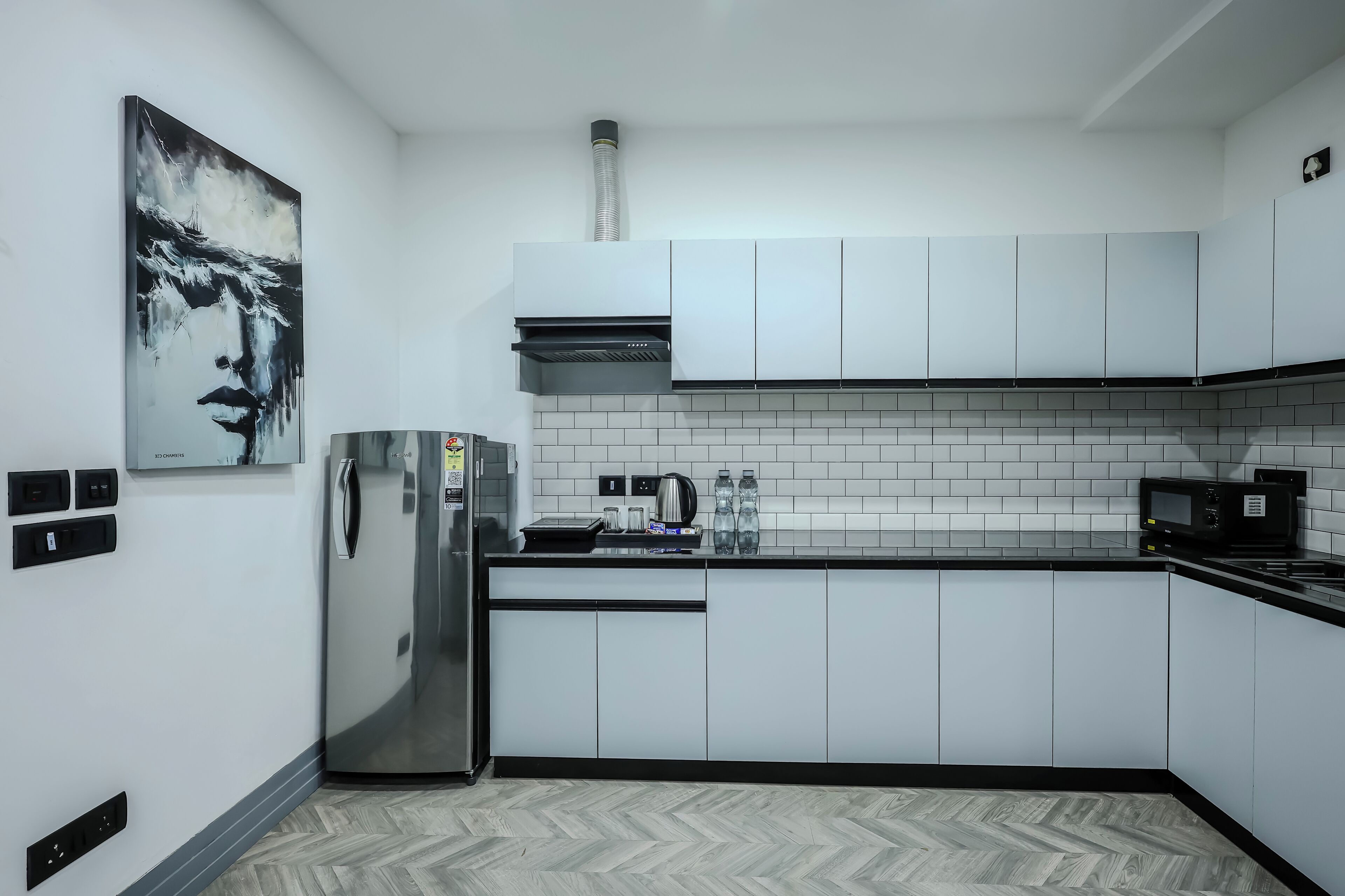 Een moderne keuken met witte kastjes, een roestvrijstalen koelkast, een magnetron en een betegelde achterwand.