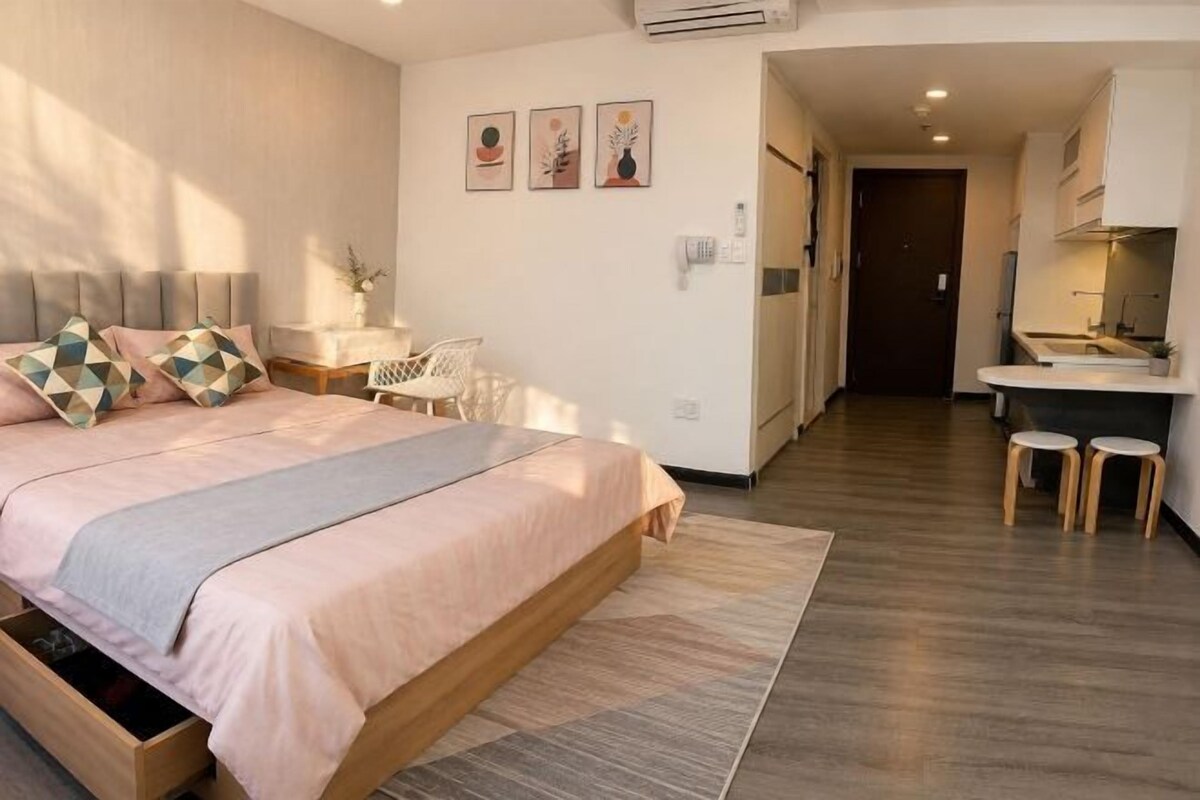 A bedroom with a bed, bedside table, and a small desk with a chair.