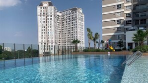 Une piscine à l’eau d’un bleu cristallin, entourée de bâtiments modernes et de palmiers.