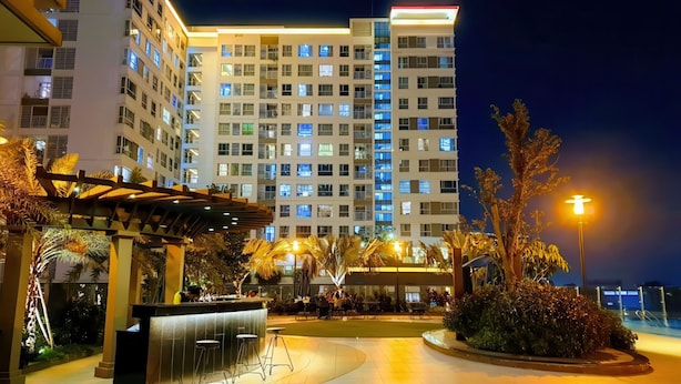 Un hôtel moderne à plusieurs étages, doté d’un espace extérieur aménagé et d’un environnement bien éclairé.