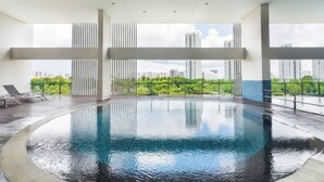 A modern indoor swimming pool with a city view, large windows, and a clean, contemporary design. - Minute Suites - Botanica Orchard TSN Air (Ho Chi Minh City)