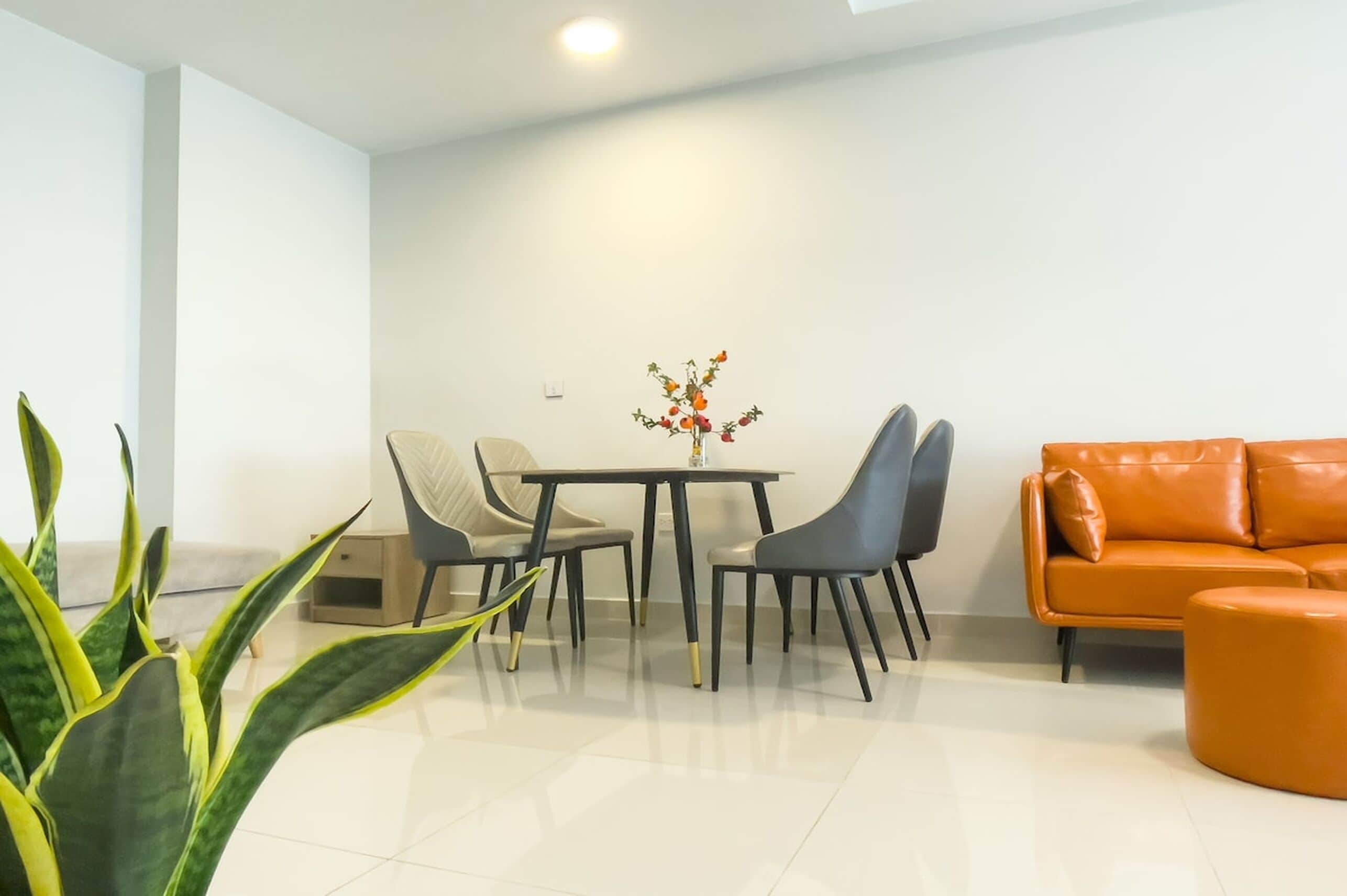 A modern living room with a dining area, a sofa, and a plant.