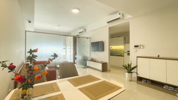 A modern hotel room with a dining area, a television, and a kitchenette. - Minute Suites - Botanica Orchard TSN Air (Ho Chi Minh City)