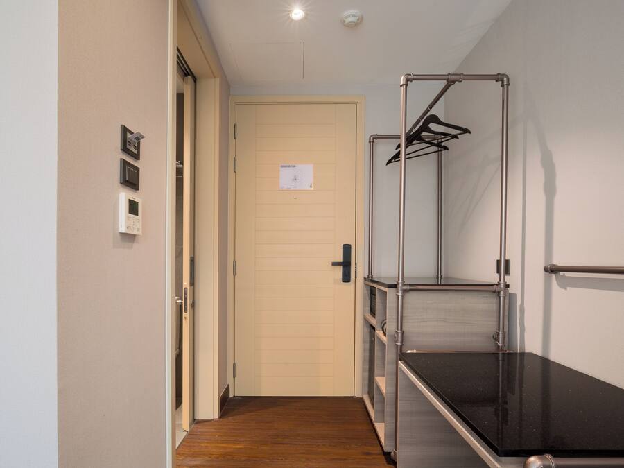 A hallway with a wooden floor, a door with a sign, and a metal rack with hangers.