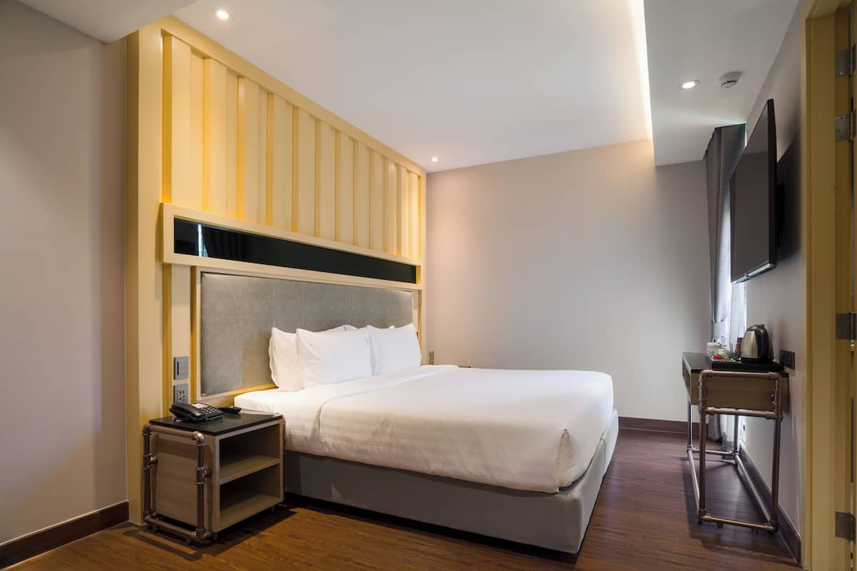 Une chambre d’hôtel équipée d’un lit, d’une table de chevet et d’un téléviseur fixé au mur.
