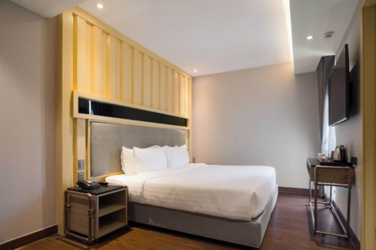 Een hotelkamer met een bed, nachtkastje en een aan de muur bevestigde televisie.