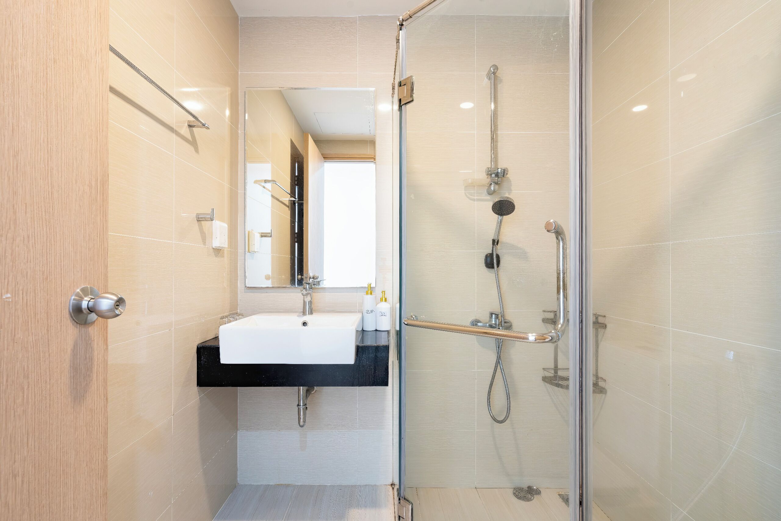 Une salle de bain moderne avec une douche à parois de verre, un lavabo doté d’un plan de travail noir et un miroir au-dessus du lavabo.
