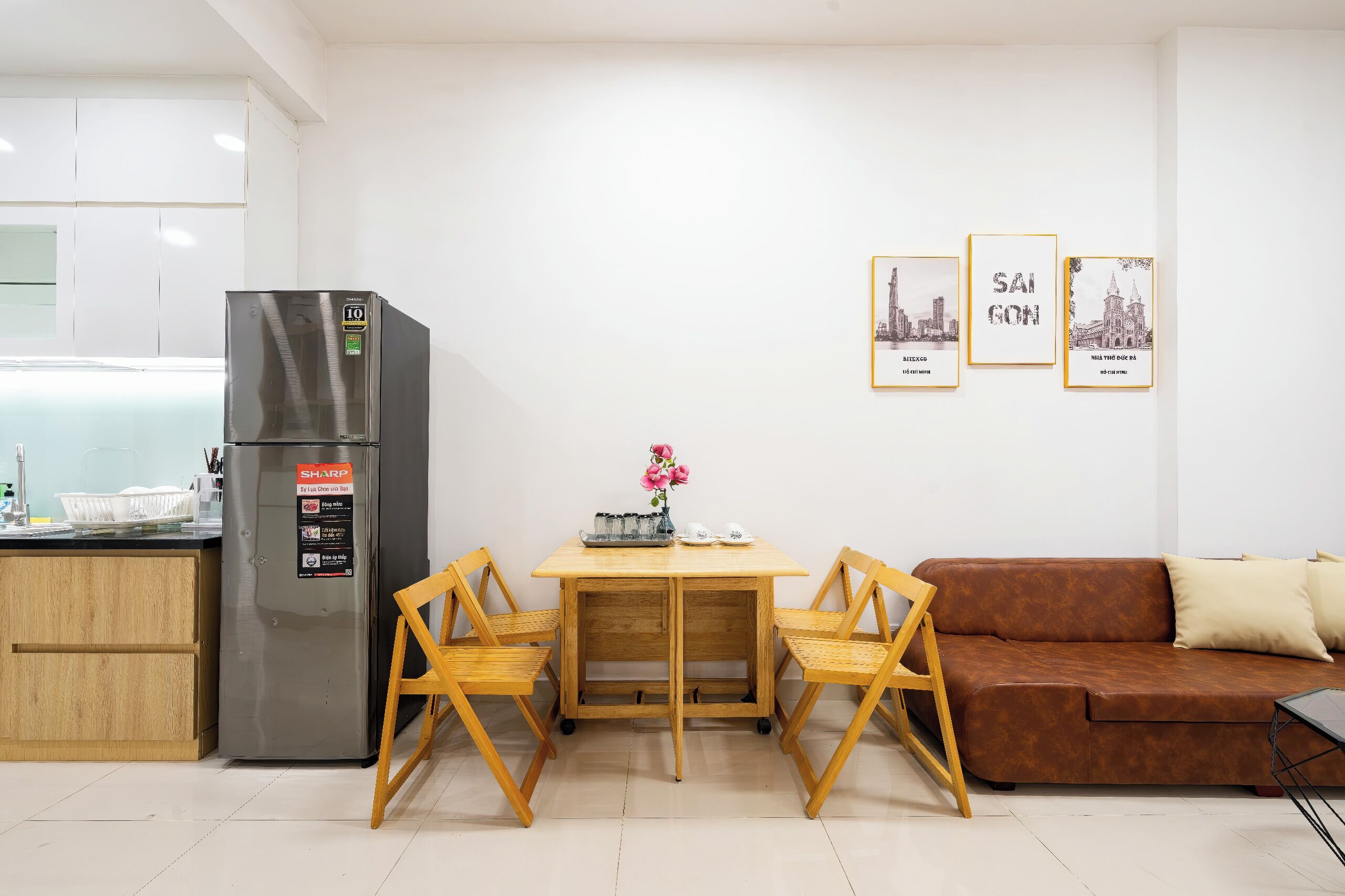 Un espacio habitable compacto con kitchenette, una mesa de comedor con sillas, un sofá y tres cuadros en la pared.